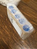 Five plastic tubes sealed with blue 'New Jersey' stickers wrapped in bubble wrap on wood surface.