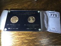 Both coins mounted on black plaque in sealed acrylic case showing overall lot