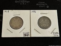 Front view of 1919 and 1998 Canadian 25 cents coins showing the reverse with denomination and wreath design. Both labeled silver 9250.