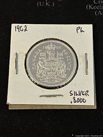 Front side of the coin showing the Canadian coat of arms and denomination '50 cents' with the year '1962'. The coin is secured in a white cardboard holder labeled '1962' and 'Silver .8000'.