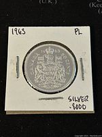 Obverse of 1963 Canadian 50 cent coin showing coat of arms, denomination, year, and silver purity marking.
