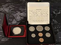 Full set of 8 coins including the 1978 Canadian silver dollar specimen set displayed in original holder and an additional silver medallion in a separate red case.