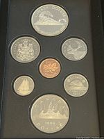 Top view of the coin set showing front sides with the 1986 Vancouver commemorative silver dollar coin at the top, surrounded by the rest of the coins.