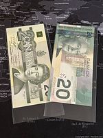 Two Canadian 20 dollar banknotes, 1991 and 2004 issue, displayed on a map background.