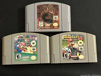 Front side view of the three Nintendo 64 game cartridges showing full color labels for Mortal Kombat Trilogy, Super Mario 64, and Mario Kart 64.
