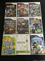 Top view of 9 assorted Wii video game cases arranged in a 3x3 grid on a dark surface, showing front cover art.