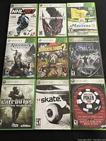 Top-down view of the 9 Xbox 360 game cases arranged in a 3x3 grid, shows all cover art clearly.