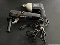 Two Black & Decker power tools on black surface: a 10mm drill and an angle grinder with cords.