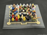 Full lot displayed on LEGO base plates showing over 55 minifigures from multiple themes