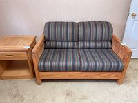 Front view of Crate Design loveseat with striped multi-color cushions and solid wood frame.
