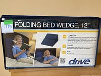 Packaging front showing the folding bed wedge in use for comfort and travel with brand and size details.