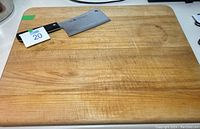 Cutting board with cleaver placed on top, showing size and wear on board surface.