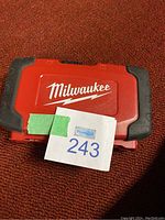 Closed red Milwaukee case with logo and auction lot number on carpet background