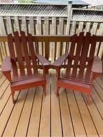 Pair of red wooden Muskoka style chairs placed side by side on a deck, showing general view of lot contents.