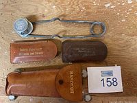 Photo showing two metal fire flints with attached circular caps and three leather pouches including one branded Handyxit.