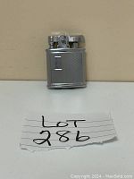 Front view of vintage Ronson silver lighter with textured and smooth panel sides and classic lighter mechanism top.