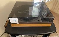 Front three-quarter view of turntable with dust cover closed, showing wood veneer base and Thorens logo.