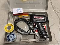 Weller soldering iron kit in metallic case along with solder paste, solder wire spool, and small tools.
