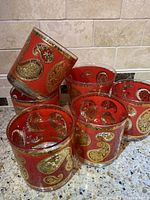 Grouping of the 5 glasses, showing four lowball and one highball style with red background and gold paisley detailing.