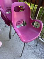 Stack of four magenta chairs showing front profile and armrests