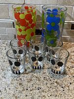 Shot glasses with skull faces and two vintage highball glasses with floral patterns on countertop