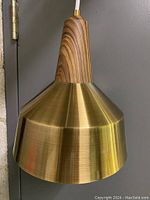 Close-up of the pendant light showing the thick wooden top section with distinctive wood grain and the brass shade below it with brushed finish.