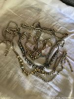 Overhead view of mixed rhinestone jewelry laid on fabric showing necklaces and earrings.