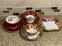 Front view of three cups and saucers with serving candy dish on a countertop.