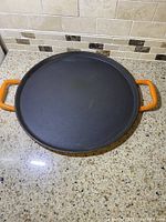 Top view of black cast iron surface with orange handles shown clearly