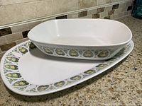 Overhead side view of the serving bowl and platter stacked, showing overall size and decorative pattern.