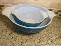 Photo showing two vintage Pyrex mixing bowls, stacked one inside the other on a kitchen countertop.