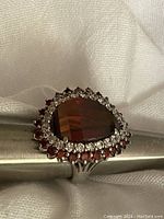 Close-up of the ring front showing the large faceted red heart-shaped stone surrounded by smaller clear and red stones