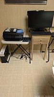 Overall view of HP printer on folding table, Lenovo monitor with keyboard and mouse on wooden side table, OmniTech shredder under table