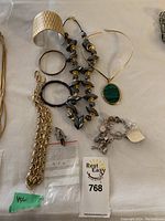 Overview photo of costume jewelry pieces showing bracelets, necklaces including YSL marked item, beaded necklace, and charm bracelet.
