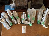 Photo showing multiple wrapped cutlery pieces including spoons, forks, knives on a wooden table