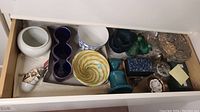 Photo of drawer holding various glass and ceramic planters and decorative items.