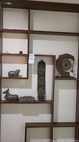 Overview of shelf displaying gong, crystal pig, wall panel and metal boxes