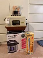 Photo of Instant Pot Ultra 60, Lovin' Oven toaster oven, and Braun MR 405 Multiquick hand mixer in original box stacked on each other.