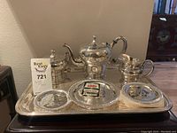 Full shot showing all items of Queen Anne silver plate tableware on the tray, including teapot, creamer, sugar bowl, and coasters.