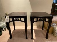 Front angled view of both rosewood side tables showing overall shape, apron carving, and legs