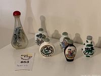 Seven snuff bottles arranged on surface showing tall glass and small porcelain examples