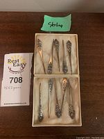 Six sterling silver picks arranged in a white cushioned box with green paper label 'Sterling' and note card showing 4.52 grams weight and seller lot number.