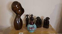 Wood carved figurines and ceramic jar arrangement on a surface