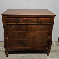 Front view of antique mahogany chest with all drawers closed, showing wood grain and brass pulls.
