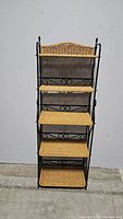 Full front view of the 5-shelf baker's rack showing wicker shelves and black metal frame with decorative scrollwork.
