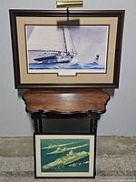 Framed watercolor painting titled 'Chasing Oysters' by John M. Barber, mounted above a small wooden stand with the vintage navy ships print below.