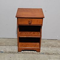 Full view of the Baumritter nightstand showing single drawer with knob and two open shelves below, finished in a nutmeg maple tone.