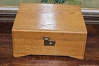Closed wood sewing box with visible grain pattern and metal clasp on front.