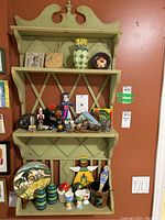 Full view of the green distressed wood display wall shelf with various items displayed showing size, color, and style.