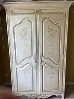 Front view of the armoire showing overall painted finish, two doors and carved details